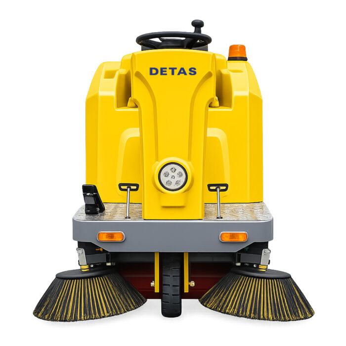 spazzatrice-industriale-detas-8500-02 Front view of a yellow street sweeper with dual side brushes and a central rotating headlight, labeled DETAS, ready for cleaning streets