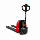Electric pallet stacker with long forks and upright handle, red and black, used to lift and move pallets in a warehouse.