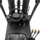 Operator-facing view in a forklift cab: steering wheel, pedal pair, and multiple joystick controls on the right, with a rugged floor mat and mast scaffolding visible in the background.