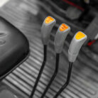 Three gray control levers with orange tips aligned in a row in a muted vehicle or machinery cockpit image