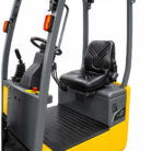 Seat and control area of a yellow and gray forklift, showing the steering wheel and joystick controls of the operator cabin.