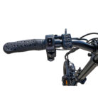 Close-up of a bicycle handlebar with a perforated grip and an electronic control pad for lights and indicators on a white background.