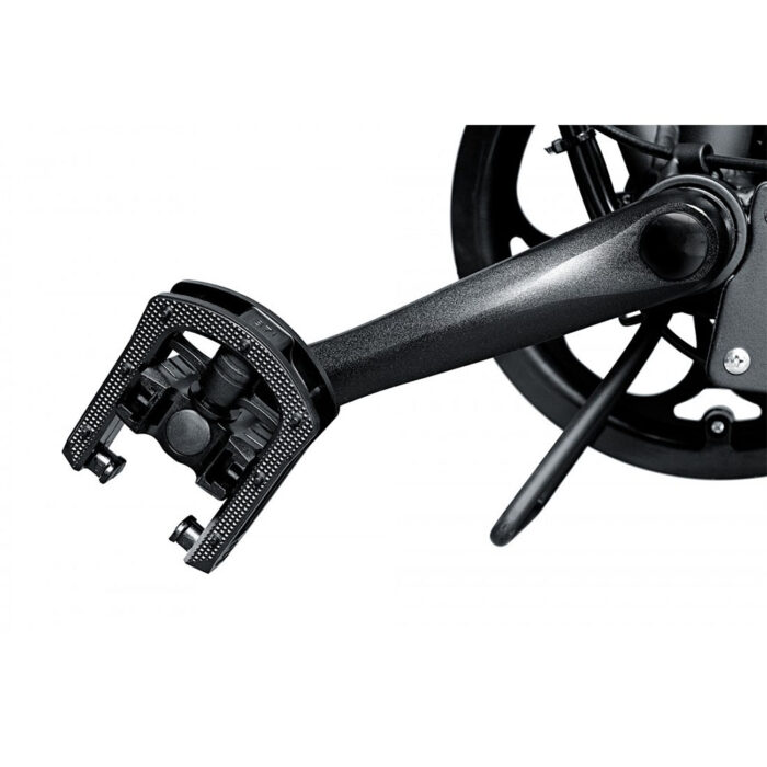 Close-up of a black bicycle pedal attached to a crank arm, showing the clipless pedal mechanism and toe area.