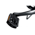 Close-up of a black clipless bicycle pedal with its binding mechanism and orange release tab attached to a bike crank arm.